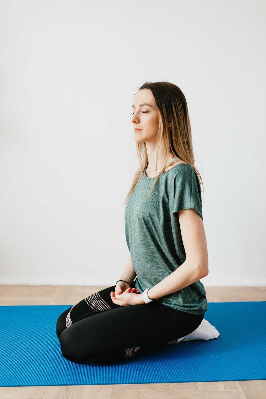 calm woman sitting in hero pose on yoga mat